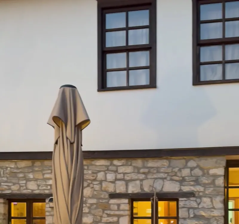 The white upper floor and dark wooden windows of Amalia Boutique Hotel above its stone ground floor